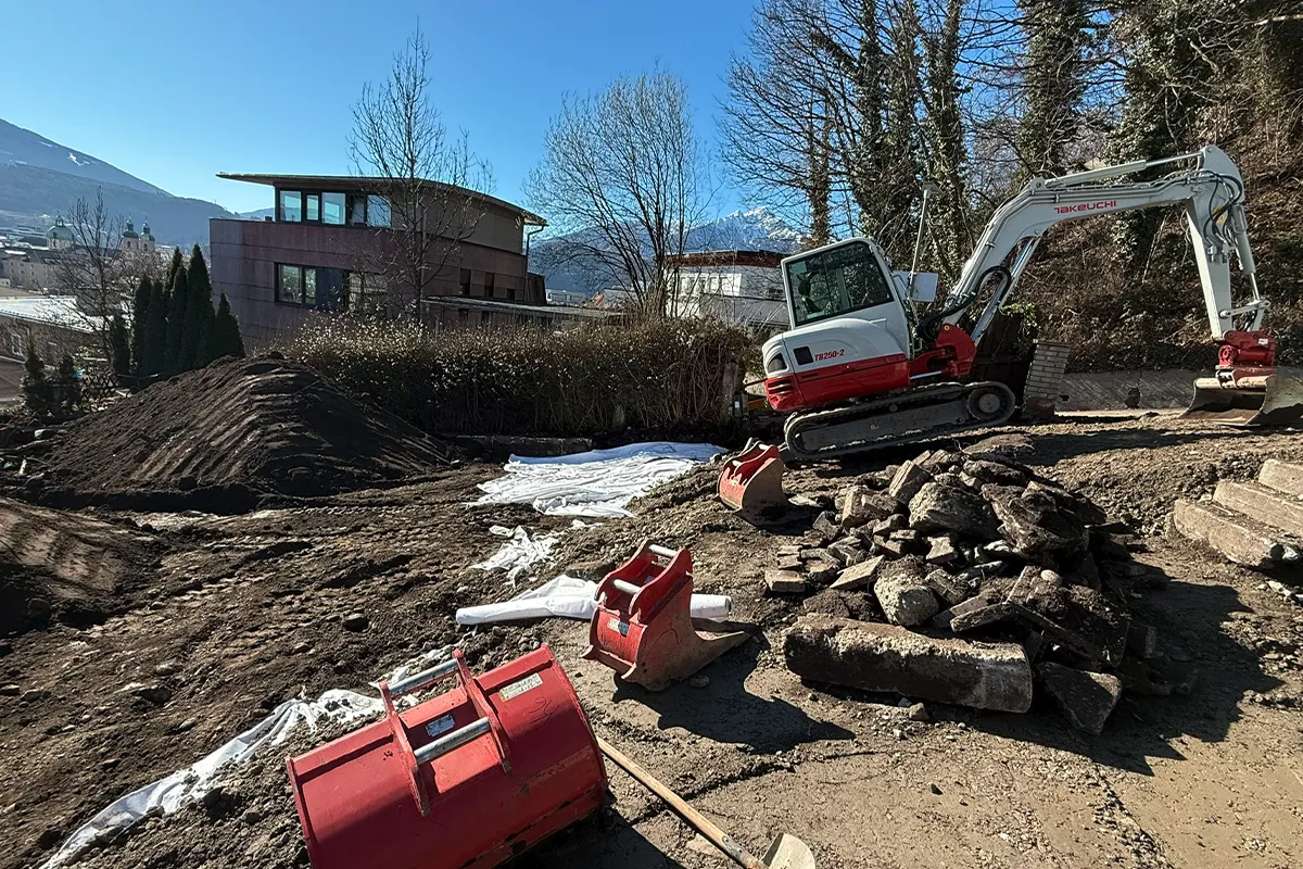 Baustelle mit Erdhaufen und Minibagger bei Aushubarbeiten