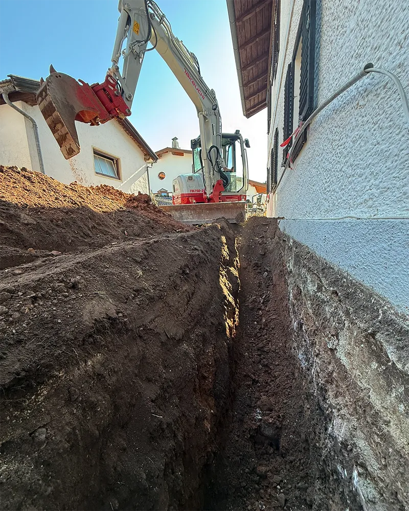 Sauber ausgehobener Leitungsgraben entlang einer Hauswand Sauber ausgehobener Leitungsgraben entlang einer Hauswand