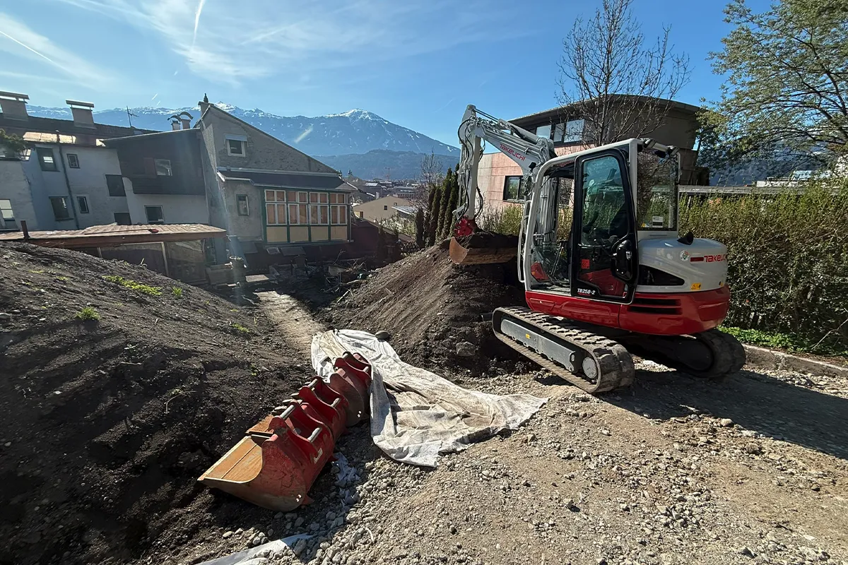 Minibagger bei Erdarbeiten auf einer Baustelle in Tirol mit Bergblick Minibagger bei Erdarbeiten auf einer Baustelle in Tirol mit Bergblick