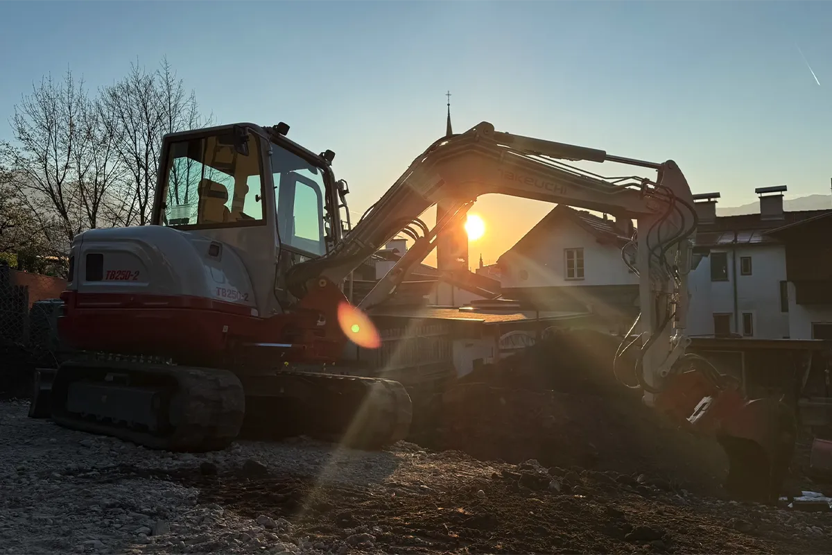 Minibagger bei Erdarbeiten im Abendlicht auf einer Baustelle Minibagger bei Erdarbeiten im Abendlicht auf einer Baustelle